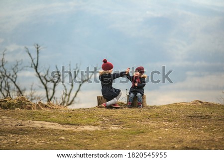 two little girls, sisters sit high in the mountains, playing palms and rock, scissors, paper. traveling with children. vacation in the winter.