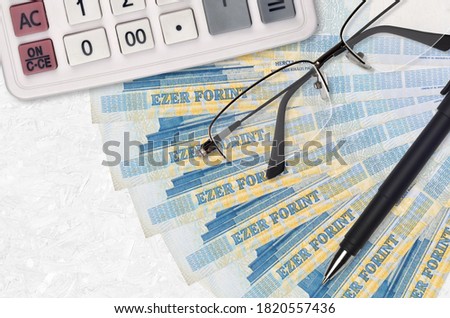 1000 Hungarian forint bills fan and calculator with glasses and pen. Business loan or tax payment season concept
