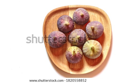 A group of fresh figs on a wooden tray with white space to place more content