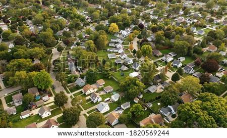 Aerial drone view of American suburban neighborhood at daytime. Establishing shot of America's  suburb. Residential single family houses pattern