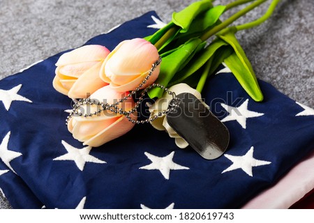 Traditional folded of America United States flag, tag and tulip flower, memorial remembrance and thank you of hero, studio shot with copy space concrete board background, USA Veterans day concept