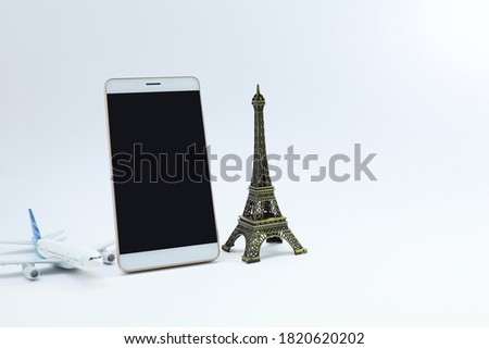 A smartphone, Eiffel tower ornament and a toy plane on white backgrond