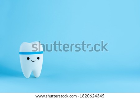 Happy smiling tooth toy on blue background with copy space. Dental care. Oral care concept, toy tooth model