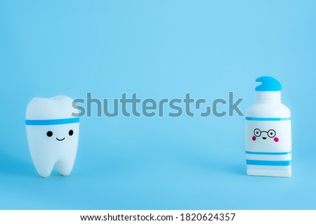 Smiling tooth and tube of toothpaste toys on blue background with copy space. Dental hygiene.