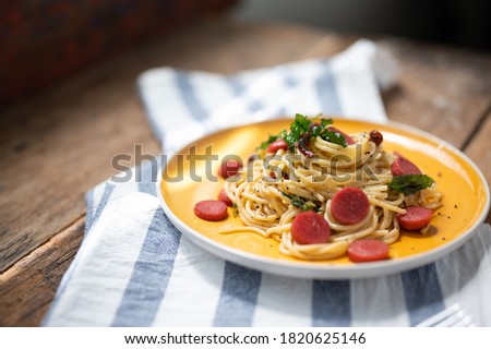Spaghetti spicy with sausage in yellow dish wood background