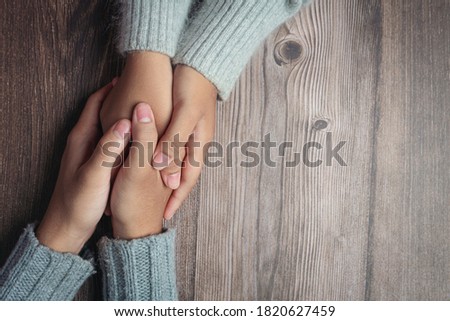 Two people holding hands together with love and warmth on wooden table Royalty-Free Stock Photo #1820627459