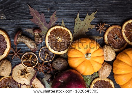 Autumn background with dried fruits, oranges, apples, nuts, anise, mushrooms, acorns and pumpkin. Dry tree leaves. Natural wooden background. Flat lay, top view, copy space. Happy Thanksgiving Day.
