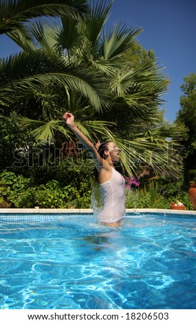 Woman jumping outside a pool with tropical palms in background