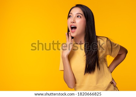 Beautiful asian girl gets surprised when look at copy space. Surprised happy beautiful asian woman looking copy space in exciting. use for your product, advertising. Isolated on yellow background