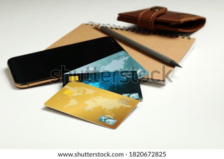 Credit cards, smartphone and notebook on white table