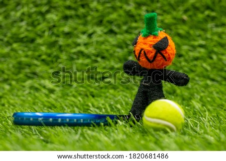 Pumpkin ghost with tennis ball on green grass for tennis player on Halloween Day