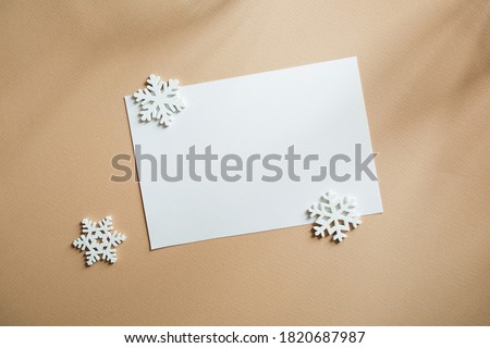 Blank white business greeting card mockup and snowflakes. on beige table backgound. minimal branding, template for winter, christmas or new year. soft shadow, copy space