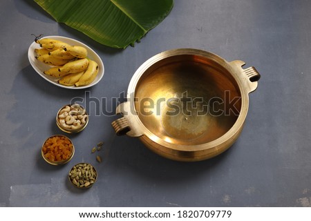 Brass vessel,south indian traditional metal vessel named urule ,which is arranged to make payasam or kheer using cashewnut,kismiss and cardamom with grey background,top view Royalty-Free Stock Photo #1820709779