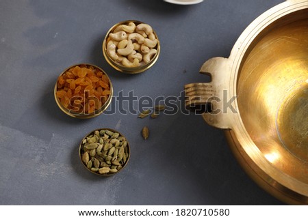 Brass vessel,south indian traditional metal vessel named urule ,which is arranged to make payasam or kheer using cashewnut,kismiss and cardamom to garnish , with grey background Royalty-Free Stock Photo #1820710580