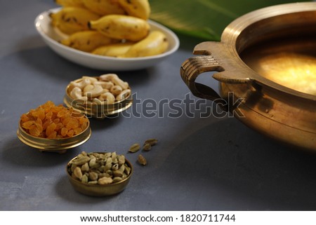 Brass vessel,south indian traditional metal vessel named urule ,which is arranged to make payasam or kheer using cashewnut,kismiss and cardamom to garnish with grey background Royalty-Free Stock Photo #1820711744