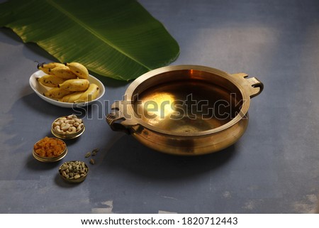 Brass vessel,south indian traditional metal vessel named urule ,which is arranged to make payasam or kheer using cashewnut,kismiss  and cardamom to garnish with grey background,selective focus Royalty-Free Stock Photo #1820712443
