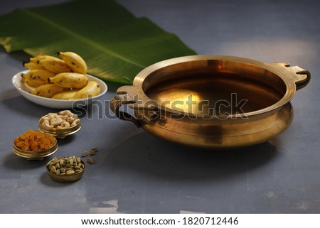 Brass vessel,south indian traditional metal vessel named urule ,which is arranged to make payasam or kheer using cashewnut,kismiss  and cardamom to garnish with grey background,selective focus Royalty-Free Stock Photo #1820712446