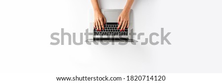 Overhead shot of female using laptop on white table. Business background. Flat lay. Banner