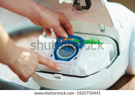 Closeup on female at home in sunny day changing vacuum cleaner bag. Royalty-Free Stock Photo #1820750441