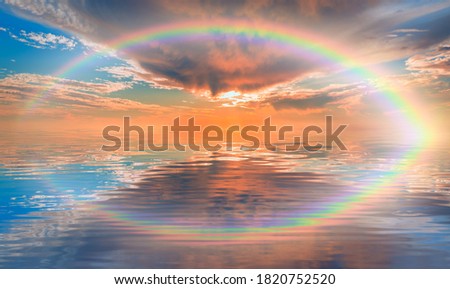 Storm on the calm sea with amazing rainbow, sunset in the background