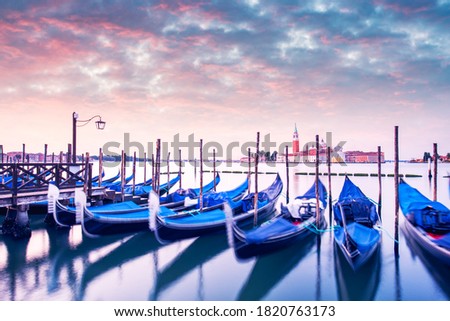 Colorful landscape with pink sunset sky on piazza San Marco in Venice. Row of gondolas parked on city pier. Church of San Giorgio Maggiore on background, Italy, Europe