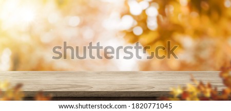 Autumn background.Empty old rustic wood table with blur forest tree with sunlight,Autumn fall backdrop, banner for product display for advertise on online,thanksgiving concept