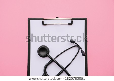 Black modern stethoscope and blank medical form on pink background. Medicine and healthcare, cardiology, medical education. Acoustic medical device. Space for text. Flat-lay, top view.