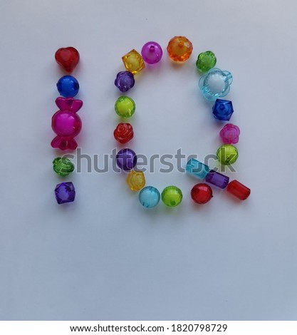 Multicolored beads of needlework in the shape of IQ on a white background