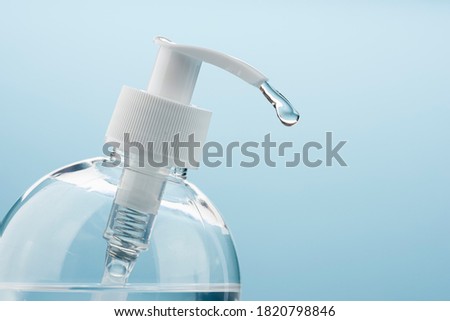 Dispenser of antibacterial gel on blue background. Close up of pump with drop.