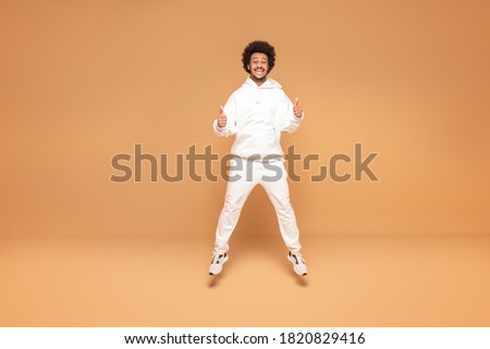 Positive afro man jumping up over studio background.