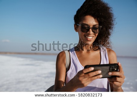 Image of happy african american woman smiling and using cellphone in salt valley