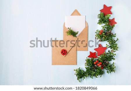 Rustic wooden blue background with Christmas empty white card and craft envelopes. Ideas for eco friendly decorations. Flat lay, top view, copy space. Minimal design mockup.