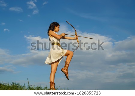young beautiful woman in white tunic with bow on sky background with clouds
