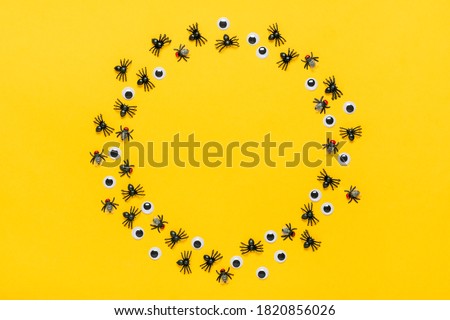 Round frame of black spiders and flies, googly eyes on yellow background Top view Flat lay Happy Halloween creative concept Holiday card Mock up