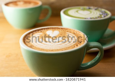 A view of several coffee latte art mugs on a wooden surface.