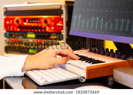 close up male music composer hands playing midi keyboard for recording on computer in sound studio