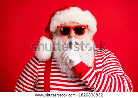 Close-up portrait of his he nice handsome mysterious white-haired Santa wearing sunglasses showing shh sign silence silent mute isolated over bright vivid shine vibrant red color background