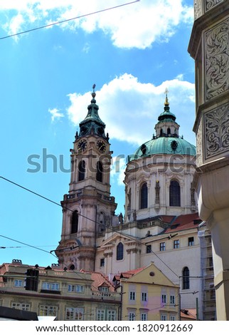 Historical bulding in Prague with blue sky. Prague and Czech Republic during sunny day. Ancient church and colorful houses in front of the church with blue and white sky background.