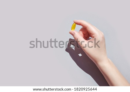 Omega 3 gel capsule. Yellow vitamin. Health eating. Dietology. Fish oil supplement. Microdosing concept. Golden color softgel collagen. Hand holding drug. Two bowl. Medicine immunity cosmetics Royalty-Free Stock Photo #1820925644