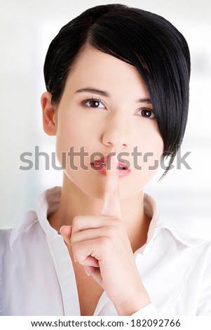 Attractive businesswoman with finger on lips, gesturing for quiet 
