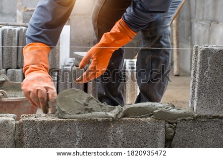 masonry worker make concrete wall by cement block and plaster at construction site Royalty-Free Stock Photo #1820935472