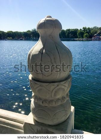 Decorative bridge handrail made of white marble looking material in front of a blue lake