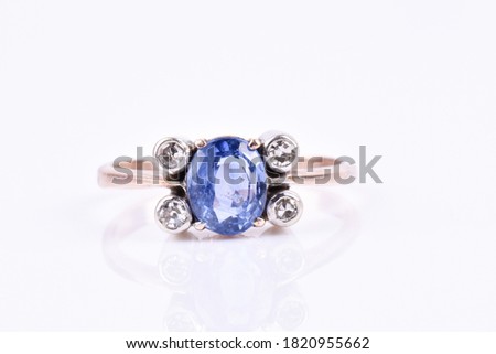 A sapphire and diamond ring on a white background