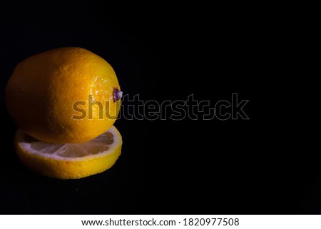 Studio photo of a whole lemon and its slice on a black background