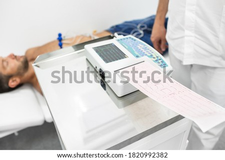 Doctor holding a cardiogram test, close-up of ECG report over a male patient. Diagnostic heart disease heart attack, tachycardia Royalty-Free Stock Photo #1820992382