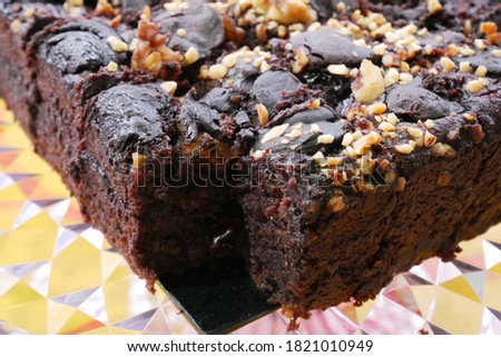 Selected focused on the chocolate cake. Rectangular in shape. Crushed almonds are sprinkled on it. Has been cut into small cubes to make it easier to eat.
