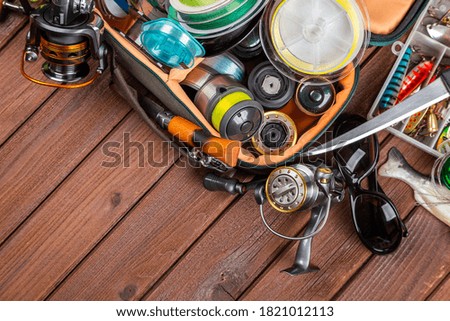 Different fishing tacles with lures and reels on wooden brown background with place for text. Design for advertisment and publishing.