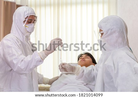 male nurse and doctor wearing ppe suit and facemask perform Coronavirus COVID-19 PCR test. patient nasal NP and oral OP swab sample specimen collection process, viral rt-PCR DNA diagnostic procedure.