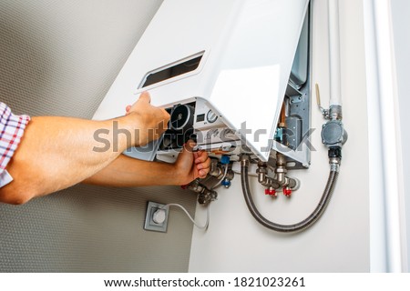 Plumber attaches Trying To Fix the Problem with the Residential Heating Equipment. Repair of a gas boiler Royalty-Free Stock Photo #1821023261