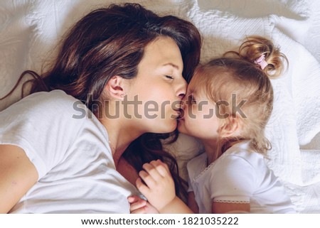 Mother kisses her daughter, top view
